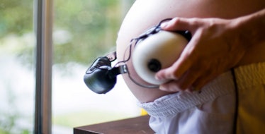A woman holding headphones on her pregnant belly