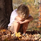sad child sitting by tree