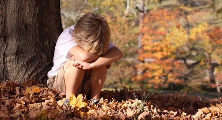 sad child sitting by tree