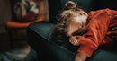 A toddler asleep on a couch.