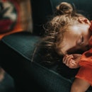 A toddler asleep on a couch.