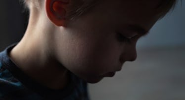 5-year-old boy with blonde hair bowing his head looking sad