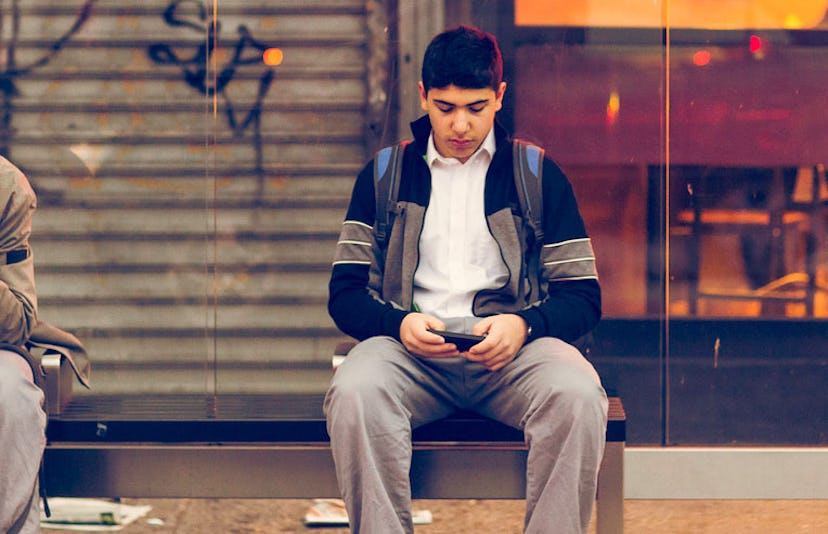 teen using phone at bus stop