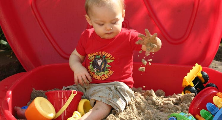 toddler playing in sandbox