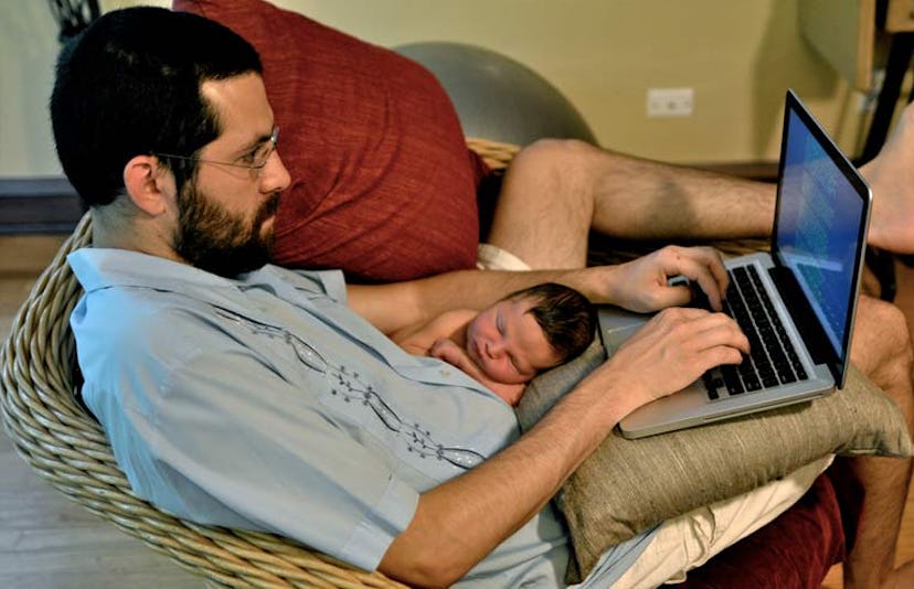 dad on computer while holding baby