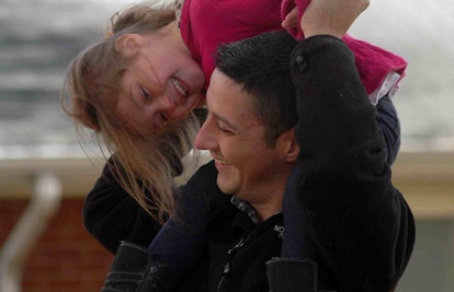 father lifting daughter over his shoulders