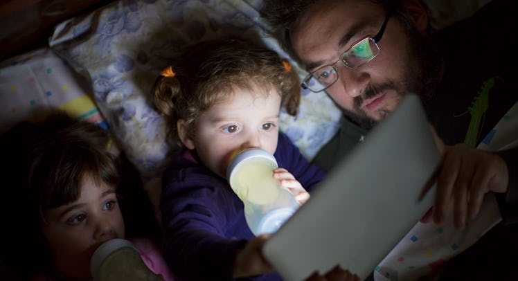 father reading to daughters on ipad