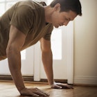 A man doing push-ups next to his bed