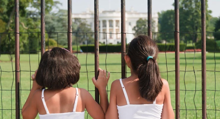 children looking at the White House through a fence
