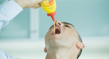 man squeezing mustard into mouth