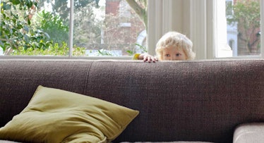 toddler hiding behind couch