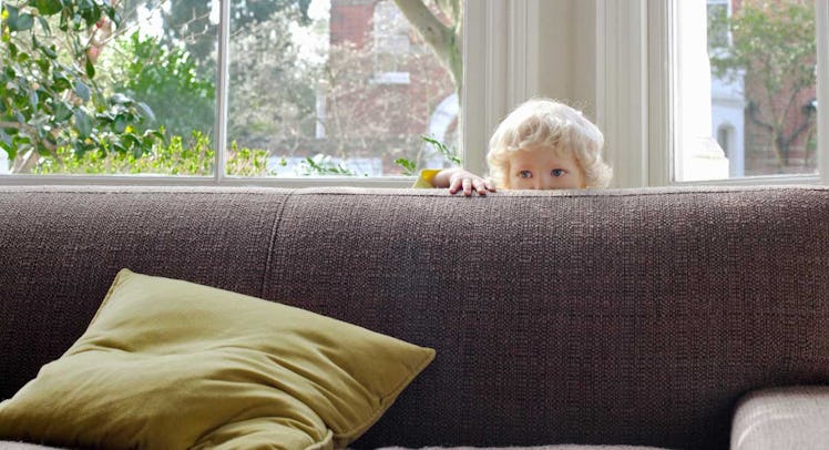 toddler hiding behind couch