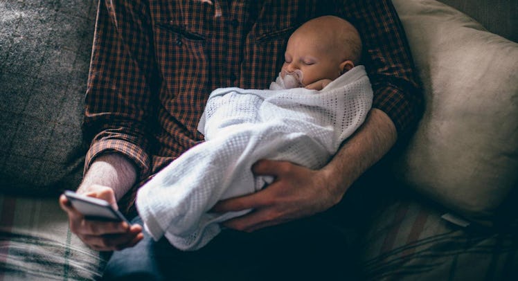 dad holding baby and checking iphone