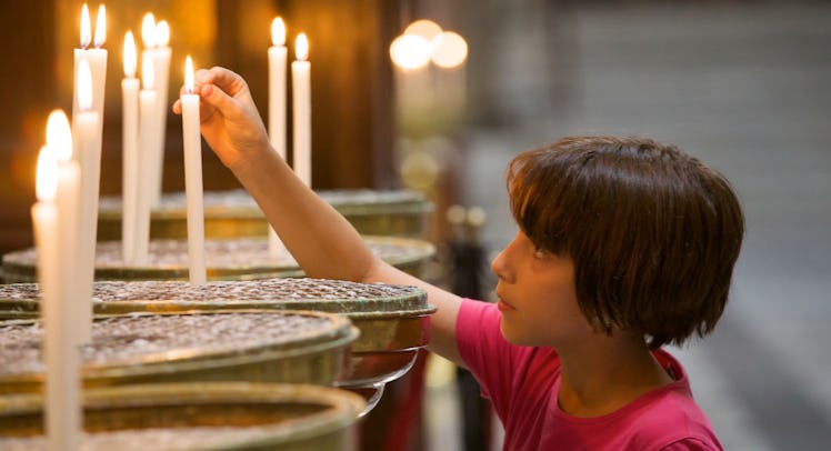 kid lighting candles in church