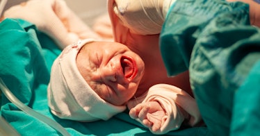 a newborn baby wearing a white knit cap and crying moments after delivery at the hospital