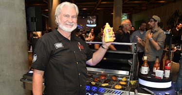 Myron Mixon holding a bottle of mustard and smiling