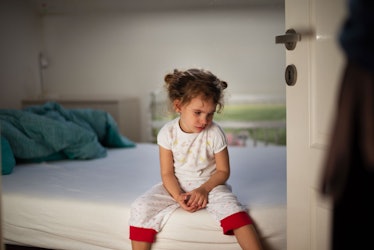 一个孩子坐在床上看起来很悲伤。对大喊大叫的反应通常以暴力或恐惧反应开始。