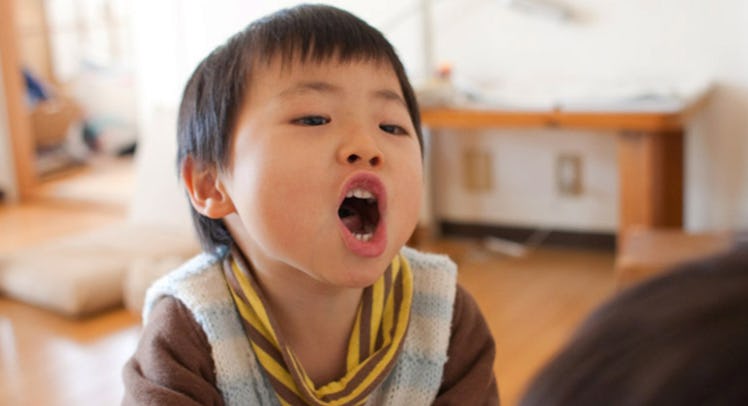 A little boy in a brown shirt and light blue sweater vest, swearing