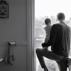 father and baby looking out window