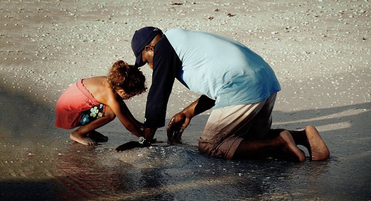 father and daughter playing in the sand