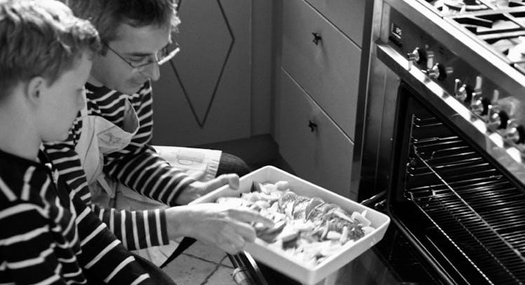 father and son putting dish in oven