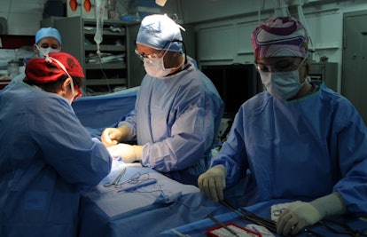Surgeons performing a laparoscopic surgery on a man's hernia 