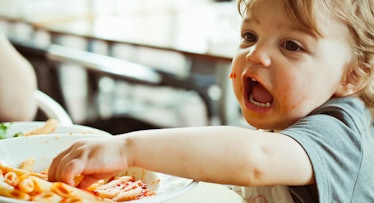 toddler eating pasta with hands