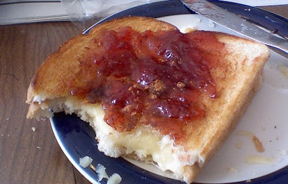 A half eaten peanut butter and jelly sandwich on a plate