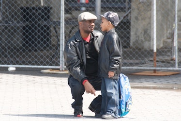 A father squatting next to his son on the street telling him something 