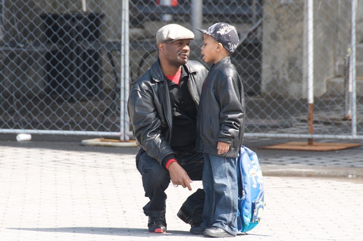 A father squatting next to his son on the street telling him something