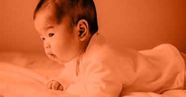 red tinted edit of newborn laying on stomach holding head up