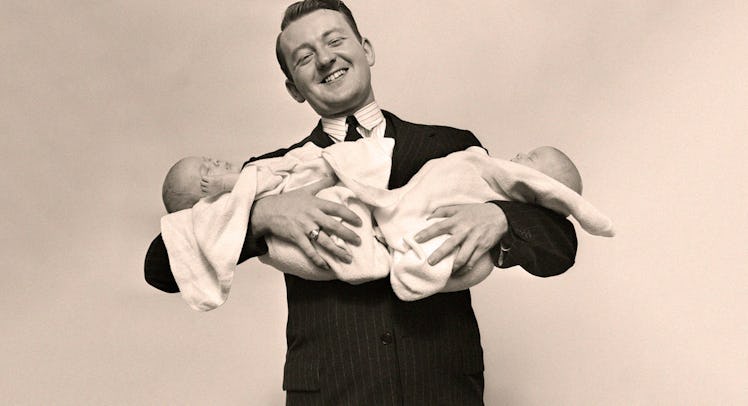 An old photo of a dad who took paternity leave holding his twin babies