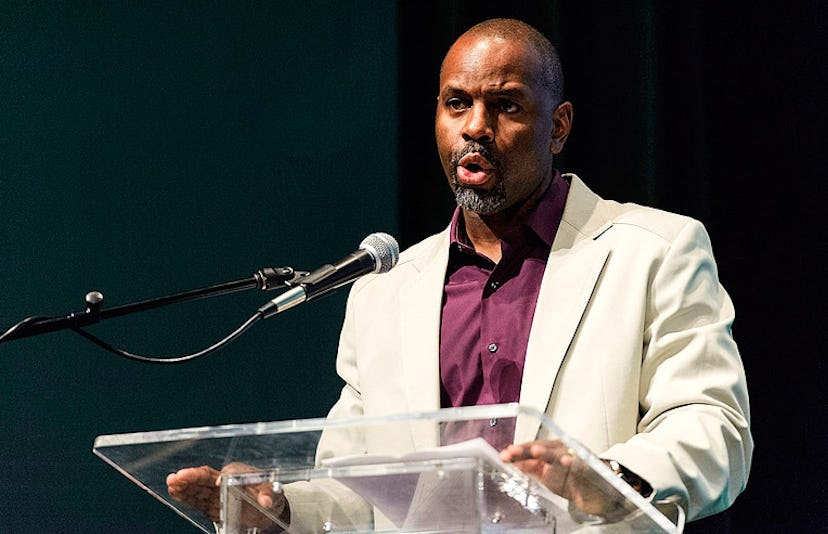 A feminist dad in a burgundy shirt and white blazer giving a speech