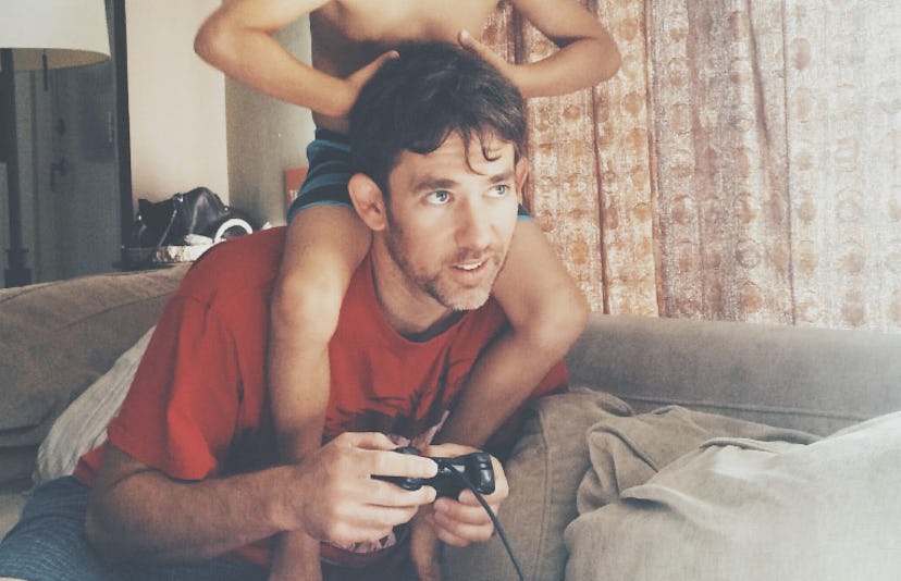 A son on his dad's shoulders while they are playing video games