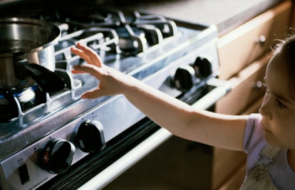 girl reaching for pan on stove