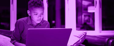 A young boy uses a laptop by himself
