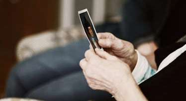 color photograph of a pair of hands holding an old faded photograph, an act of nostalgia