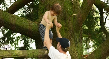 dad helping son climb tree