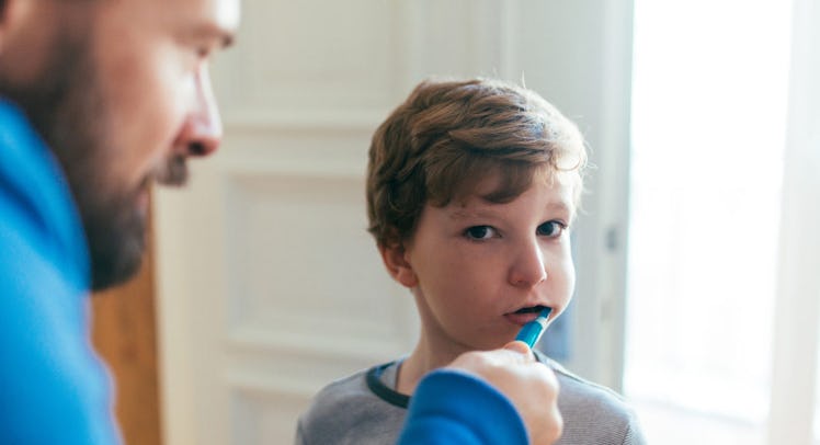 dad helps kid brush teeth