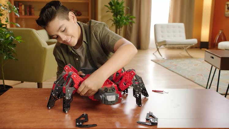 A happy boy playing and building his tough toy in a shape of a spider