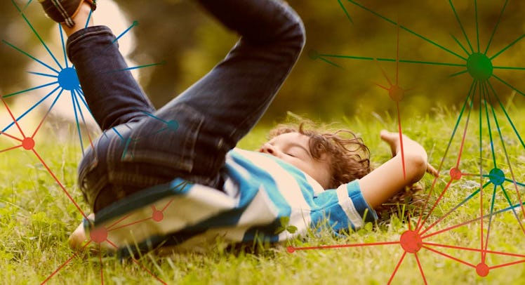 A young boy lying and playing in the grass