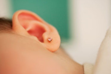 A closeup image of a baby's ear with an earring in it.