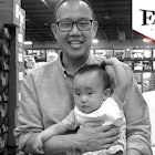 Chieh Huang holding his child with a "Father of the Year" sign above him