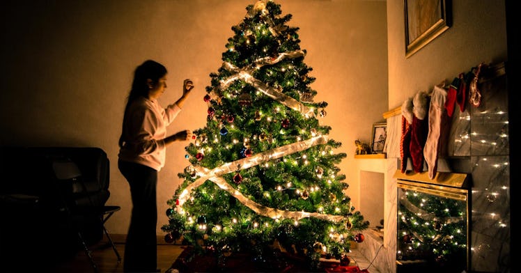 A girl decorating a Christmas tree in a living room