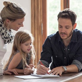A mom, dad and their daughter calculating the cost of education on a notepad