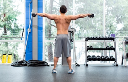 A young man doing dumbbell lateral raise exercise at a gym