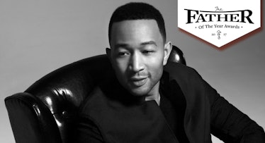 John legend in a black suit sitting in a leather chair. father of the year award logo next to him