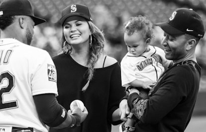 John Legend holding his daughter while standing next to his wife meeting a pitcher for the boston re...