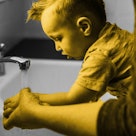 A parent helps a child wash their hands to prevent the flu.
