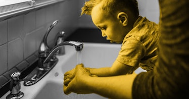 A parent helps a child wash their hands to prevent the flu.